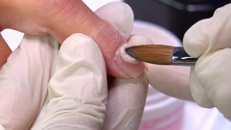 Nail technician applying acrylic