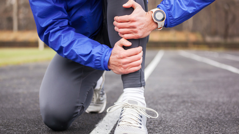 Person kneeling during run holding shin