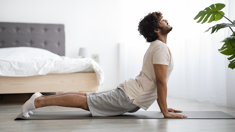 Young man doing yoga in bedroom