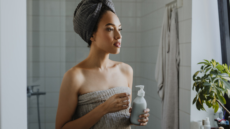 Woman holding lotion in bathroom