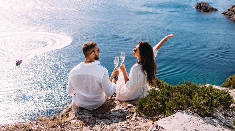 Couple sitting on cliff by ocean 