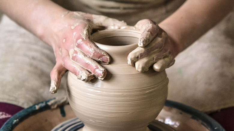 Two hands making pottery