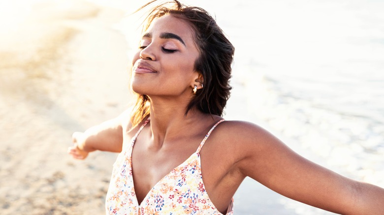 Black woman holding arms out on the beach