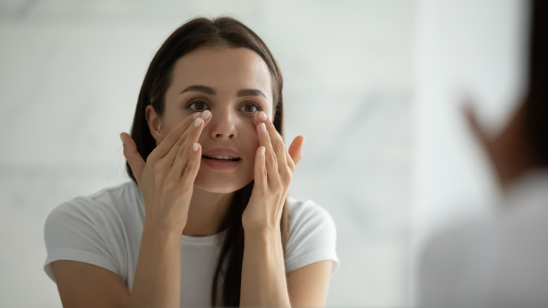 woman applying skincare in mirror