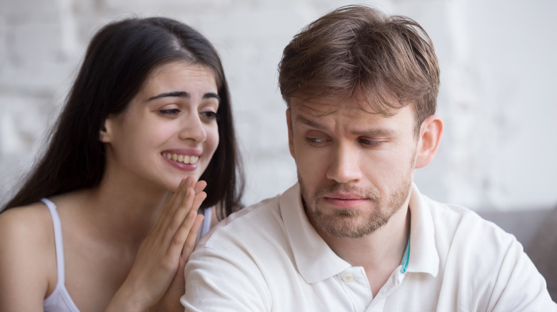 Woman smiling at upset man