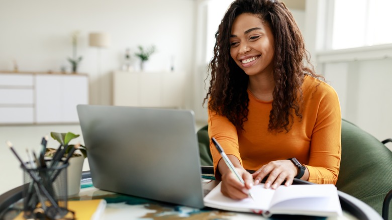 Woman smiling with laptop and notebook